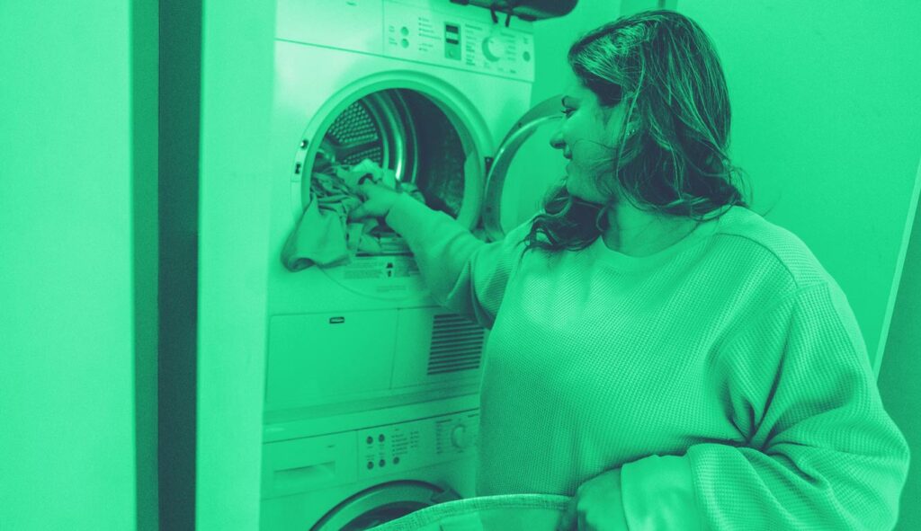 Donna che tira fuori i panni dalla lavatrice, si occupa della cura della famiglia